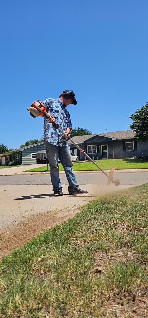 A local crew member trimming the edge of an Oklahoma lawn